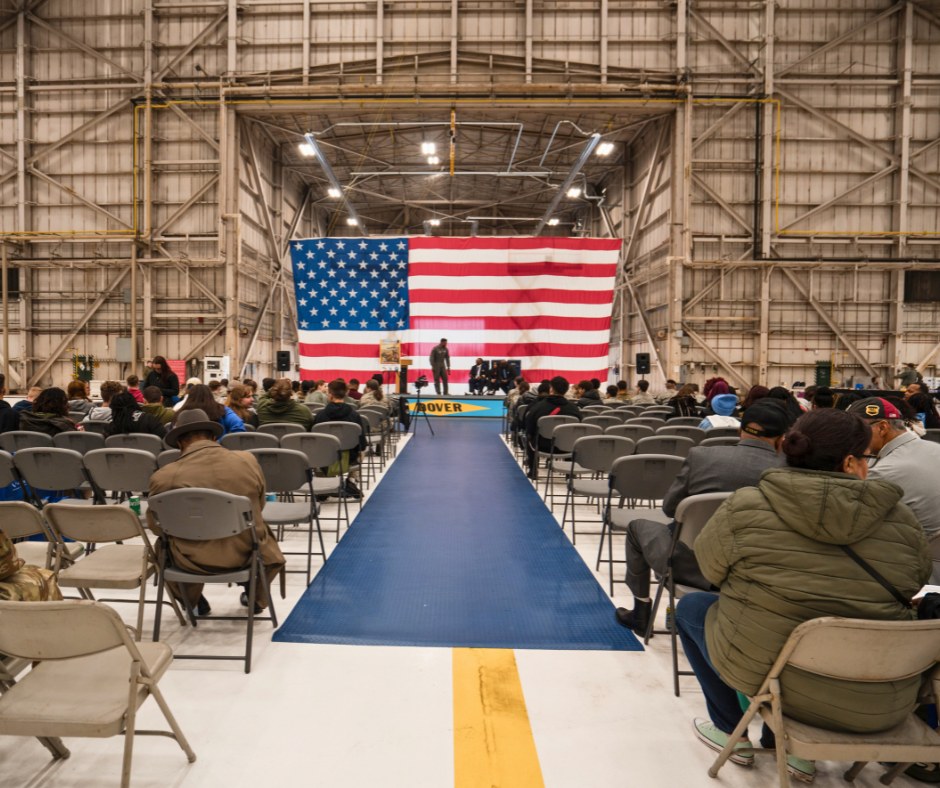 Picture of the Tuskeegee event venue- inside of an aircraft hangar with an American Flag backdrop