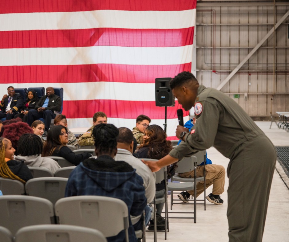 Soldier walks around attendees at the Tuskeegee event presenting with a microphone