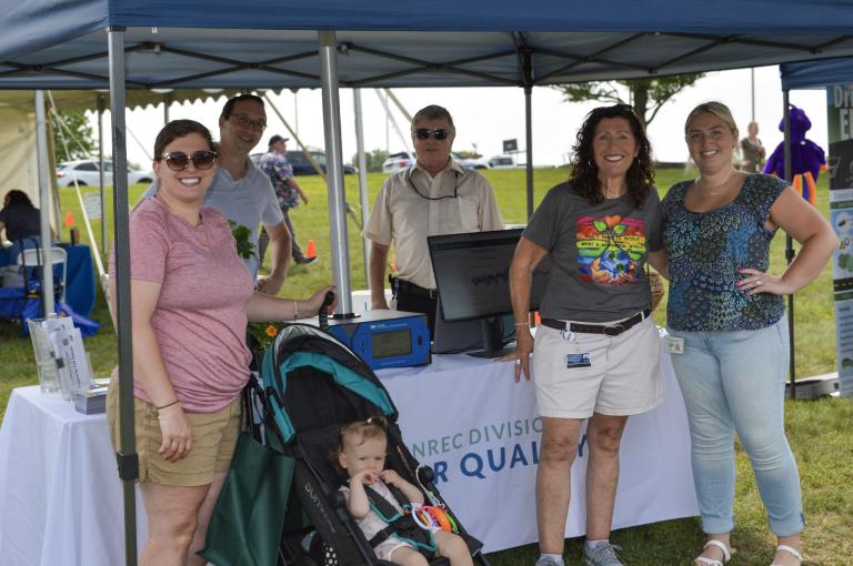 A group of smiling guests at the DNREC booth at the World Environment Day event at Veteran's Memorial Park