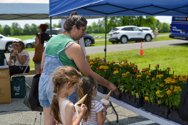 A mother and her daughters picking out flowers at the flower booth World Environment Day event at Veteran's Memorial Park