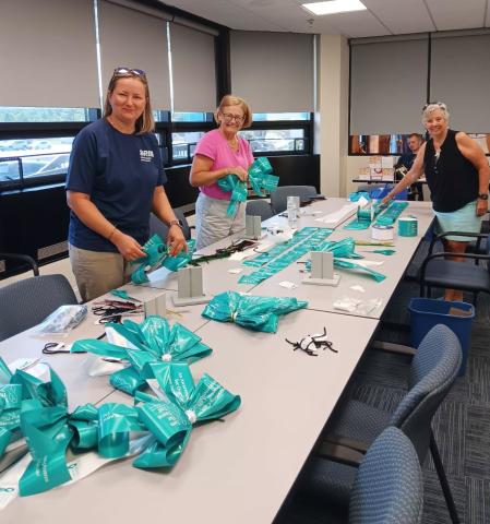 DRBA staff hand-tie bows for the Turn the Towns Teal campaign