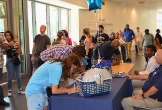 Job fair attendees fill out papers at a DRBA booth